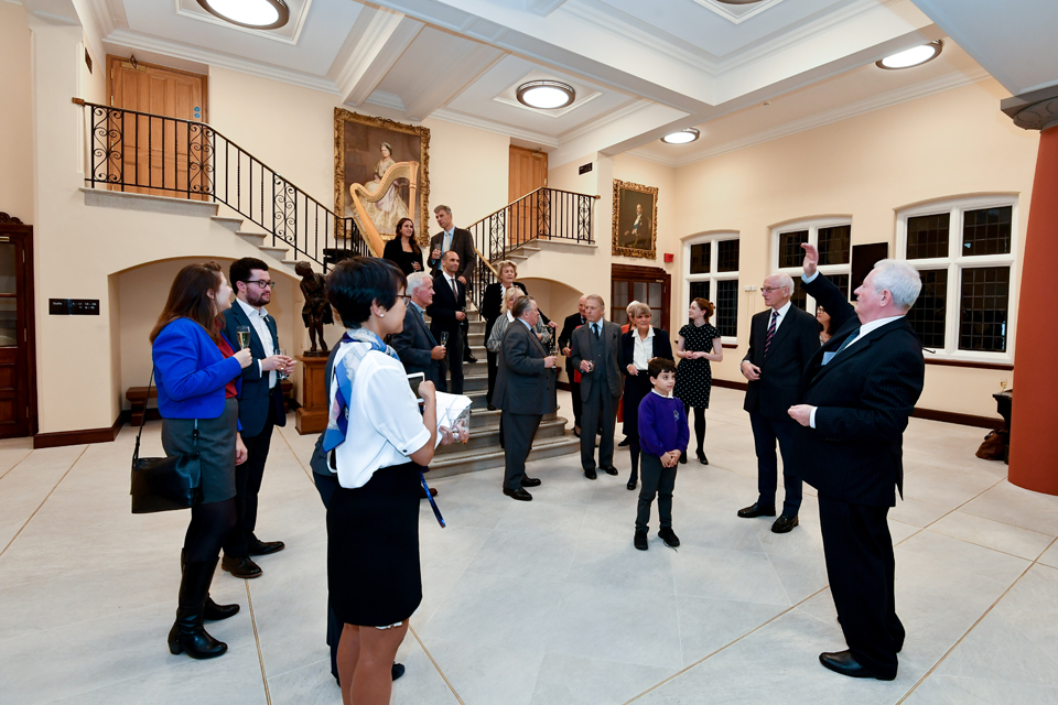 A group of people in a well lit room, holding glasses of champagne, celebrating.